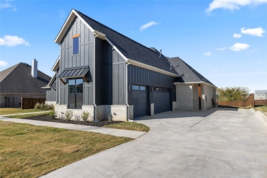 View of front facade featuring board and batten siding, driveway, a shingled roof, brick siding, and a standing seam roof