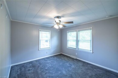 Primary Bedroom: Features include carpet flooring to help keep your feet warm on cool mornings, 3 windows for natural lighting with blinds for privacy, fresh new paint, a ceiling fan with light and decorative crown molding