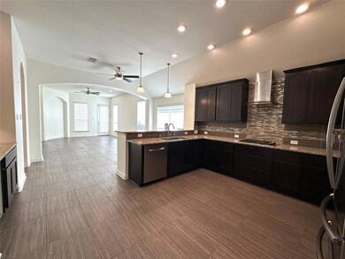 Kitchen featuring arched walkways, hanging light fixtures, light stone counters, backsplash, and recessed lighting