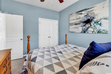 Carpeted bedroom featuring ceiling fan and a close