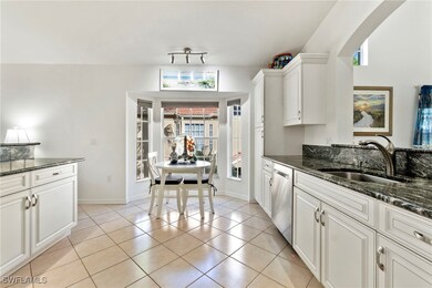 Kitchen with dark stone countertops, light tile patterned flooring, and white cabinets