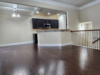 Kitchen featuring dark cabinetry, dark wood-type flooring, stainless steel microwave, a breakfast bar, and crown molding