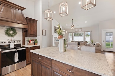 Kitchen with stainless steel electric range oven, backsplash, light wood-style flooring, ceiling fan, and custom range hood