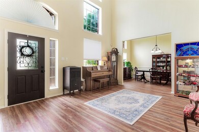 The formal living room welcomes you with warm wood-like flooring, sunny windows and 20' ceiling.