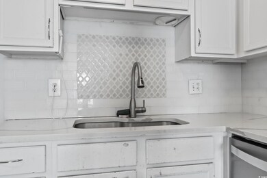 Kitchen with sink, white cabinets, and backsplash