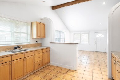 Kitchen with a sink, light countertops, vaulted c