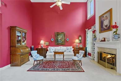 Carpeted living room with a high ceiling, ceiling fan, a premium fireplace, and baseboards