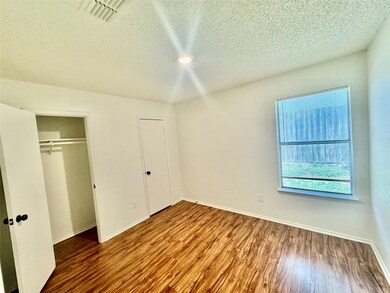 Unfurnished bedroom with a textured ceiling, wood