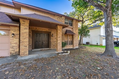 Doorway to property with a shingled roof, brick siding, and a garage