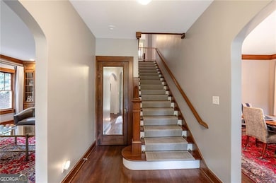 Staircase featuring arched walkways, wood finished floors, and crown molding