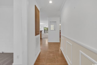 Hall featuring ornamental molding and light tile patterned flooring