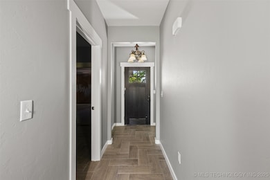 Hall featuring baseboards and a chandelier