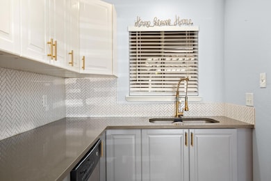 Kitchen with a sink, backsplash, white cabinetry,