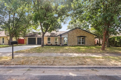 View of front of house with a front yard, brick siding, driveway, and an attached garage