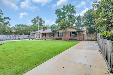 Ranch-style home featuring brick siding, a chimney, and concrete driveway
