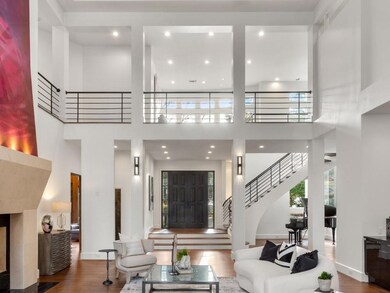 Living room with a high ceiling, recessed lighting, dark wood-style flooring, a fireplace, and stairs