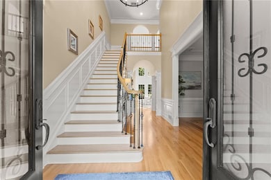 Entryway featuring stairs, a wainscoted wall, ligh