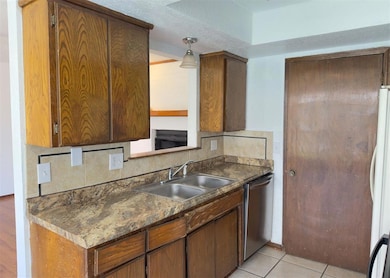 Kitchen with decorative backsplash, dark countertops, dishwasher, brown cabinets, and a textured ceiling