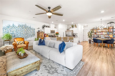Living room featuring light wood-style floors, a ceiling fan, recessed lighting, and a chandelier