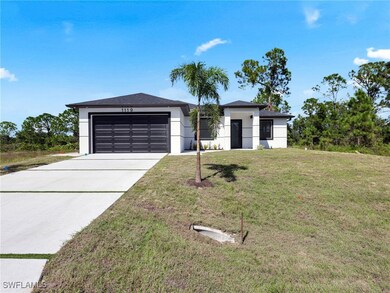 View of front facade with a front yard, concrete driveway, stucco siding, and a garage
