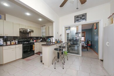 Kitchen featuring decorative backsplash, a peninsula, black range with gas stovetop, dark stone countertops, and under cabinet range hood