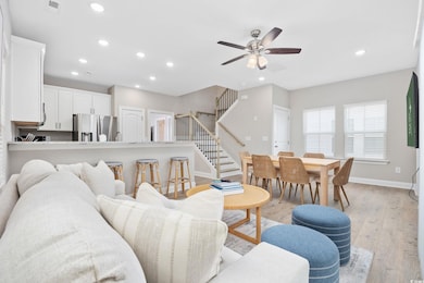 Living area featuring stairway, a ceiling fan, lig