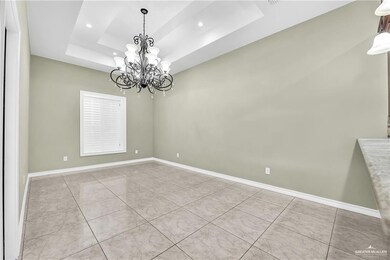 Empty room with a tray ceiling, an inviting chandelier, and light tile floors