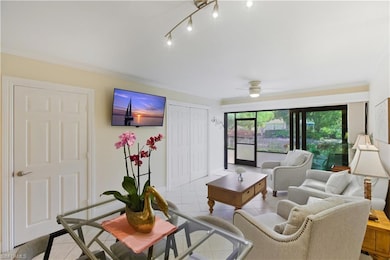 Living area with tile patterned flooring, crown molding, and a ceiling fan