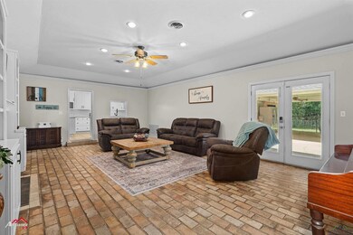 Living room with a ceiling fan, brick flooring, crown molding, recessed lighting, and a raised ceiling