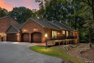 View of front of home featuring an attached garage, driveway, brick siding, and a wooden deck