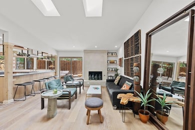 Living room with light wood-type flooring, healthy amount of natural light, a fireplace, a skylight, and recessed lighting