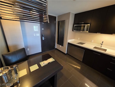 Kitchen with dark cabinetry, a sink, stainless ste