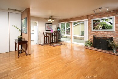 The spacious family room adjoins the kitchen and is bathed in natural light from the large sliding glass door to the backyard, plus it’s further enhanced by complimentary hardwood flooring, plus its floor-to-ceiling wood burning brick fireplace with 