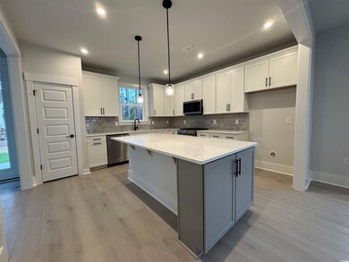 Kitchen featuring white cabinetry, pendant lighting, a center island, light wood-type flooring, and recessed lighting
