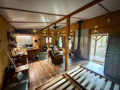Living area featuring wood finished floors, a wood stove, ceiling fan, healthy amount of natural light, and wooden walls
