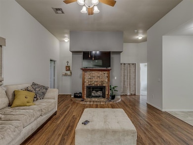 Living area featuring ceiling fan, a fireplace, and wood finished floors