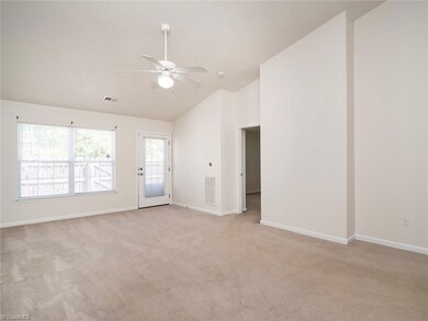 Large living room with vaulted ceilings and access to back yard. Notice the ceiling fan!