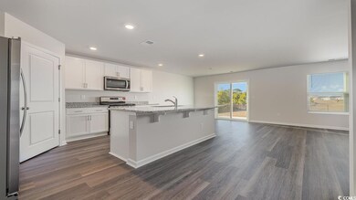Kitchen with white cabinetry, appliances with stai