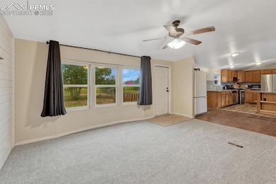 Unfurnished living room featuring plenty of natural light, light colored carpet, and ceiling fan