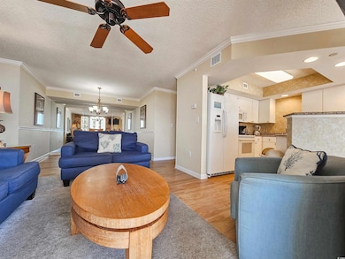 Living room with a chandelier, light wood finished floors, ceiling fan, a textured ceiling, and baseboards
