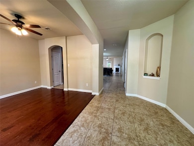 Empty room featuring ceiling fan, arched walkways