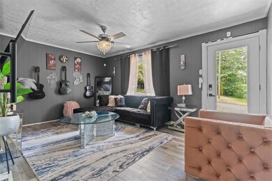 Living area featuring healthy amount of natural light, ceiling fan, a textured ceiling, wood finished floors, and crown molding