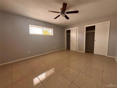 Unfurnished bedroom featuring two closets, tile patterned floors, baseboards, and a ceiling fan
