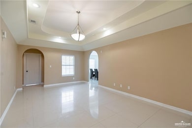 Unfurnished room featuring arched walkways, baseboards, light tile patterned floors, a tray ceiling, and recessed lighting