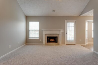 Living room w/ fireplace, opens to Kitchen.