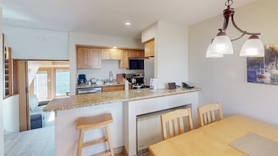 Kitchen with a breakfast bar, a peninsula, stainless steel appliances, light stone counters, and hanging light fixtures