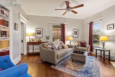 Living area featuring wood-type flooring, a ceiling fan, and baseboards