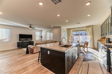 Kitchen with a breakfast bar area, recessed lighting, a kitchen island with sink, open floor plan, and light wood-style floors