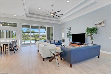 Living area featuring a tray ceiling, a ceiling fan, recessed lighting, light wood-type flooring, and baseboards