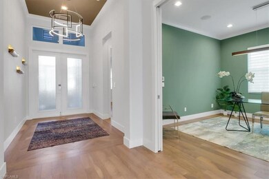 Foyer with a chandelier, wood finished floors, french doors, and baseboards